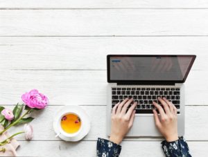 macbook pro beside white cup and saucer on table